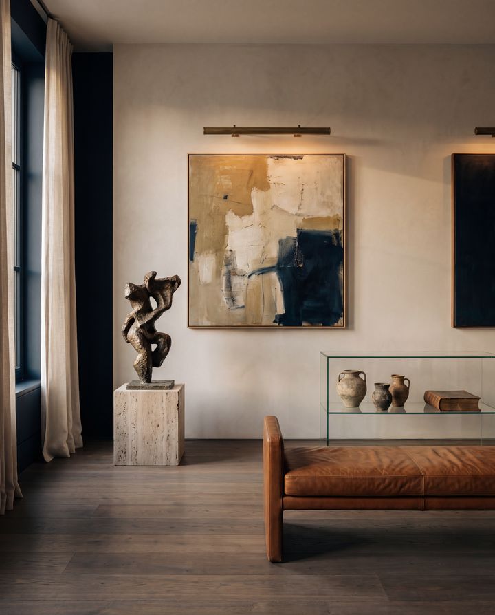 A private gallery room: an abstract painting, a bronze sculpture on a travertine plinth and a leather bench.