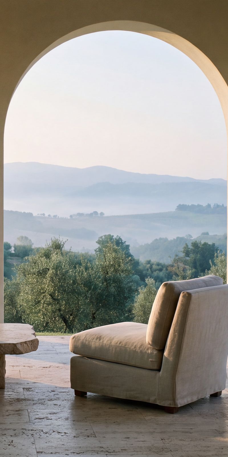 A stone loggia of arches at dawn, two linen chairs facing olive groves and hills.